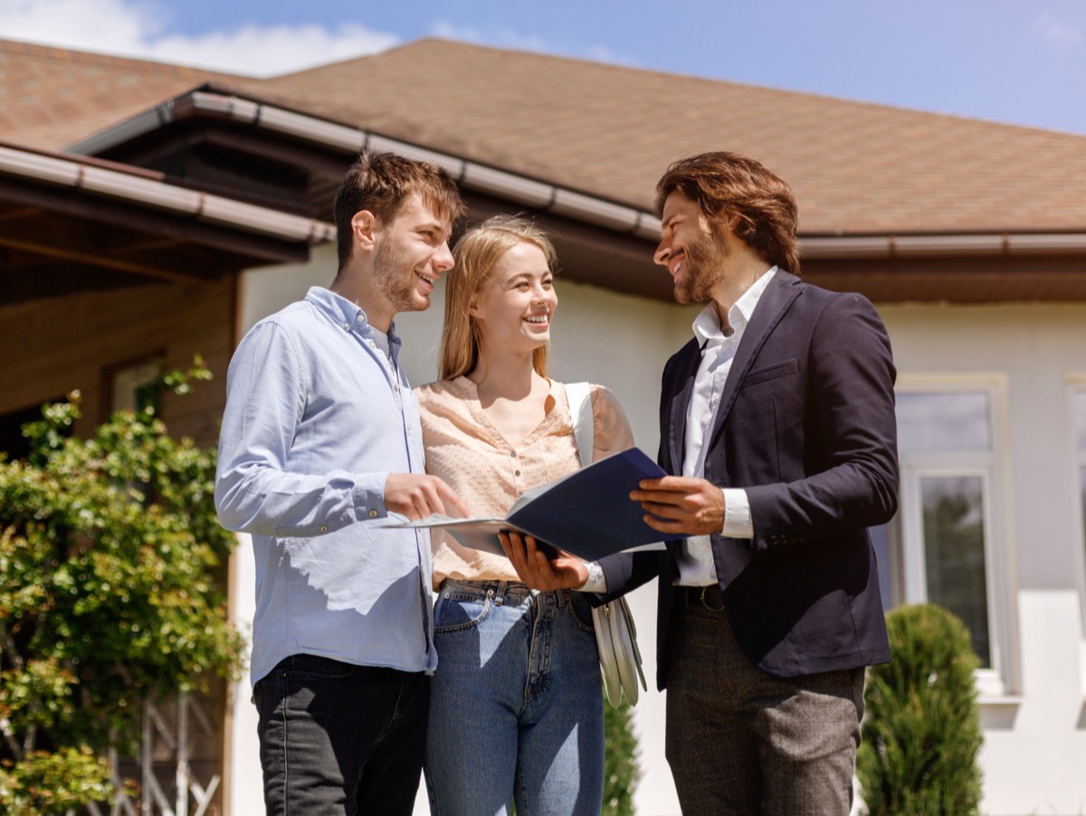 An adviser going through a sale agreement with a couple outside a home