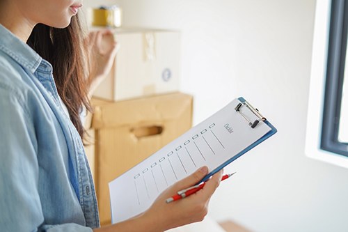 Executor reviewing a probate checklist on a clipboard beside packed moving boxes